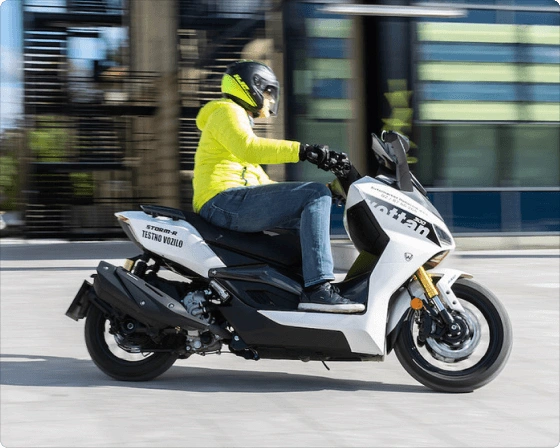 Beli skuter Storm-R CBS z moškim med vožnjo